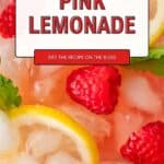 Pink lemonade in tall glasses with slices of lemon and strawberries.