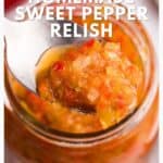 A spoonful of chunky, colorful sweet pepper relish held over an open jar.