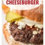 Close-up of a bacon cheeseburger with pickles, cheese, and a toasted bun; website link at the bottom.