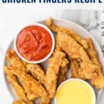 A plate of crispy fried chicken fingers with red and yellow dipping sauces, seen from above.