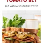 A fried green tomato BLT sandwich with lettuce, bacon, and sauce on toasted bread, displayed on a wooden board.