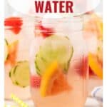 A mason jar of infused water with cucumber, lemon, and strawberry slices, and ice cubes.