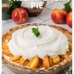 A fresh peach pie topped with fluffy sour cream filling, garnished with mint, surrounded by whole peaches.