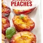 Grilled peach halves arranged on a white platter, garnished with fresh basil leaves.