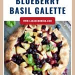 A rustic galette filled with pineapple, blueberries, and basil, garnished with fresh basil leaves.