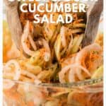 A bowl of sweet and sour cucumber salad with shredded carrots, being served with wooden salad tongs.