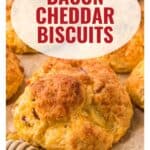 Close-up of golden bacon cheddar biscuits on parchment paper, with text overlay Bacon Cheddar Biscuits.
