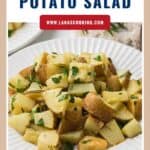A plate of roasted potato salad with fresh herbs, served on a white dish.