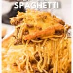 A cheesy slice of baked spaghetti with meat sauce being lifted from a casserole dish.