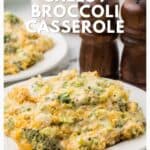 A serving of cheesy broccoli casserole on a white plate, with pepper mills in the background.