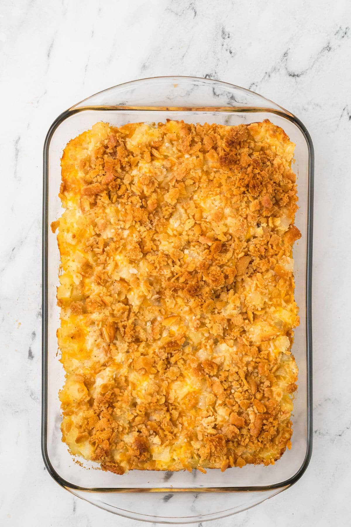 Baked casserole topped with golden, crispy crumbs in a glass dish on a white marble surface.