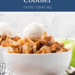 A bowl of apple cobbler topped with a scoop of vanilla ice cream.