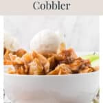 A bowl of patchwork apple cobbler topped with a scoop of vanilla ice cream.