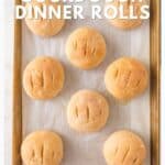 Golden-brown sourdough rolls on a baking sheet with text overlay about a no-knead recipe.