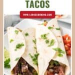 Two carne asada tacos on a white plate, topped with cilantro, with a website link above them.