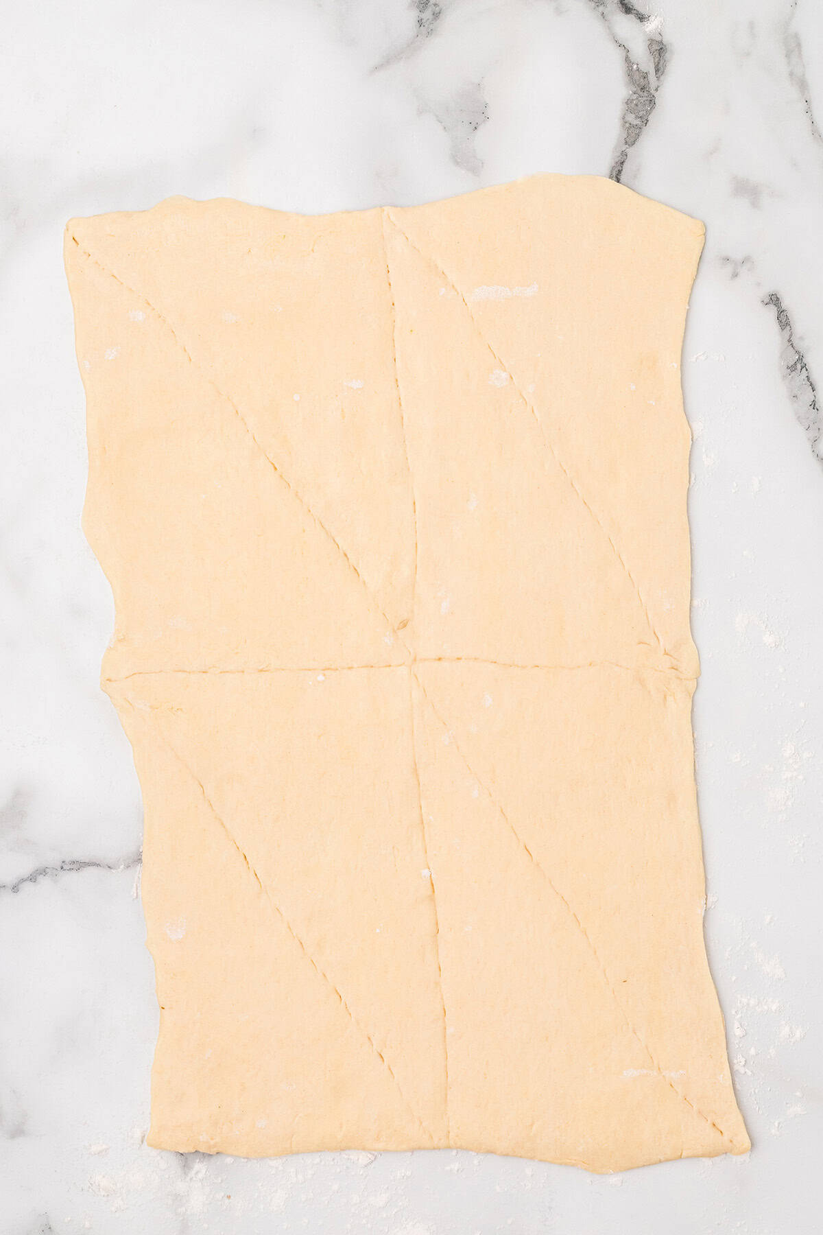 Rectangle of crescent roll dough on a floured marble surface,