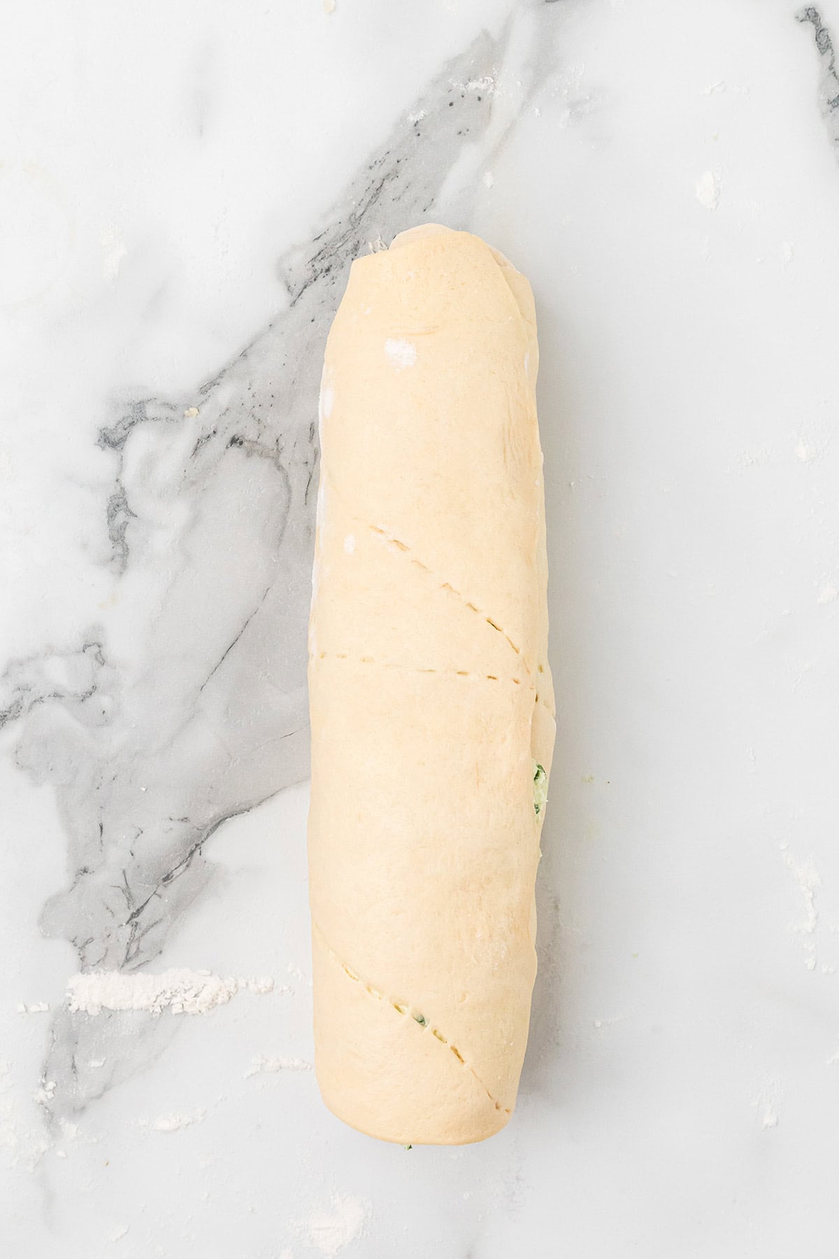 Unbaked rolled dough on a marble surface, lightly dusted with flour.