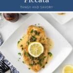Chicken piccata topped with a lemon slice and capers on a white plate.