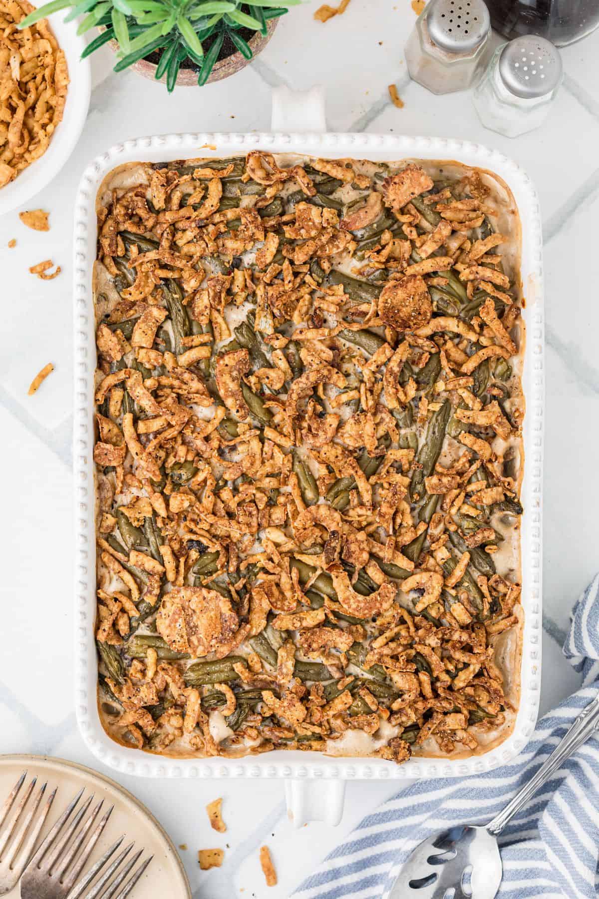 A casserole dish filled with green bean casserole topped with crispy fried onions on a white countertop.