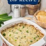 Baked artichoke dip in a white dish, garnished with green onions, next to crackers and fresh green onions.