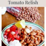 Bowl of pinto beans with tomato relish, sour cream, and a lime wedge.
