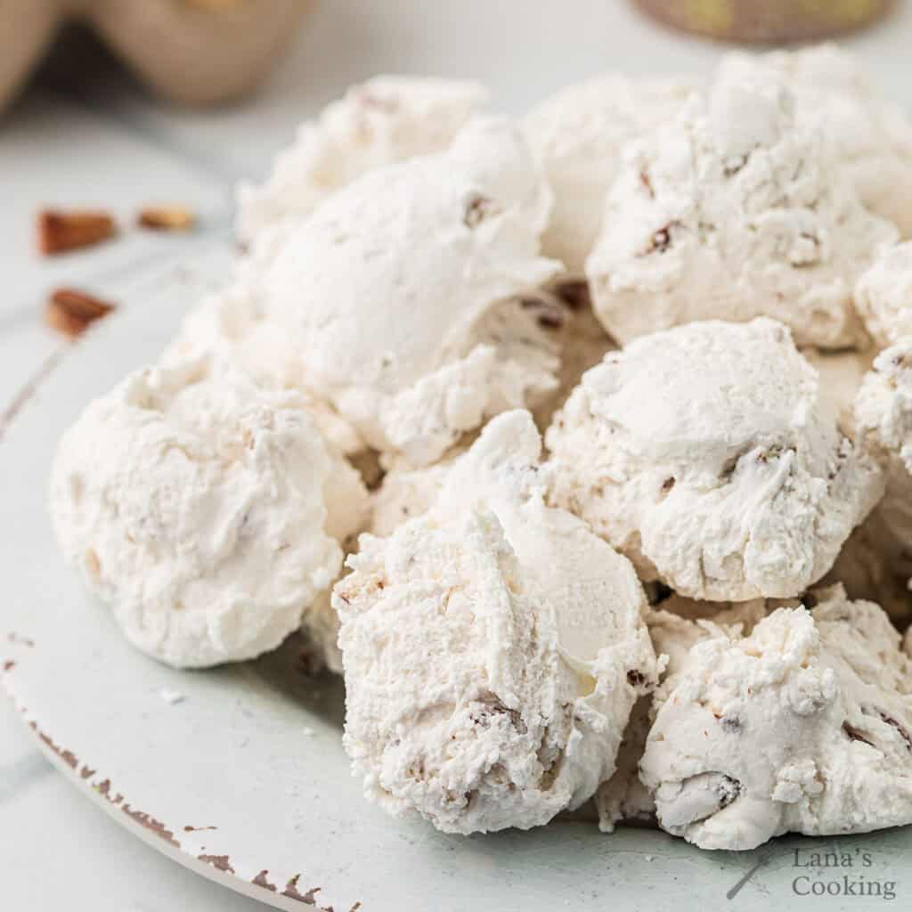 Divinity candy with pecans piled on a white plate.