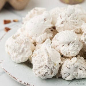 Divinity candy with pecans piled on a white plate.