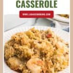 A plate of baked seafood casserole with shrimp and breadcrumbs, shown in front of a recipe website banner.