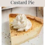A slice of Old Fashioned Egg Custard Pie topped with whipped cream and spices on a white plate.