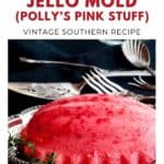 A pink raspberry jello mold on a silver platter, with serving utensils in the background.