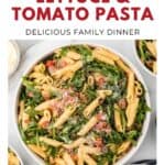 Bowl of penne pasta with bacon, lettuce, tomatoes, and parmesan on a white table, seen from above.