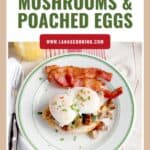 Plate with poached eggs on creamed mushrooms, bacon strips, and toast, next to fork, knife, and a drink.
