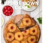 A pineapple upside down cake on a wooden board, topped with pineapple rings and cherries.