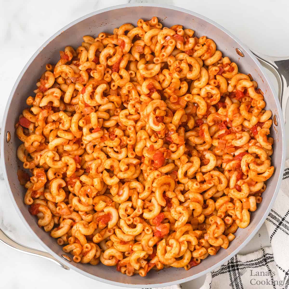 A skillet filled with cooked macaroni pasta mixed in a red tomato-based sauce.