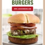 A meatloaf burger with lettuce, onion, and tomato on a plate, topped with a hamburger bun.