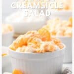 White ramekin of orange creamsicle salad with mandarin segments and marshmallows, text above and website below.