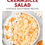 Bowl of orange creamsicle salad with mini marshmallows and orange slices, text overlay with recipe title.