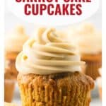 Carrot cake cupcake topped with swirled frosting, with more cupcakes blurred in the background.