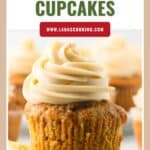 Carrot cake cupcake with cream cheese frosting, unwrapped, with more cupcakes in the background.