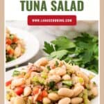 A plate of white bean tuna salad with chopped vegetables, garnished with parsley, next to another plate.