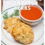 Plate with two herb biscuits and a cup of tomato soup on a white napkin, garnished with fresh dill.