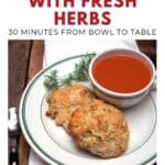 Plate with two herb biscuits, fresh dill, and a bowl of tomato soup on a wooden table.