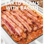 A casserole dish filled with baked beans topped with several strips of cooked bacon.
