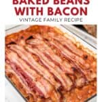 A baking dish filled with baked beans topped with strips of crispy bacon, shown on a white background.