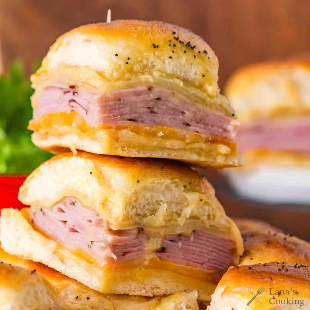 Two ham and cheese sliders stacked on top of each other, with golden buns and melted cheese.