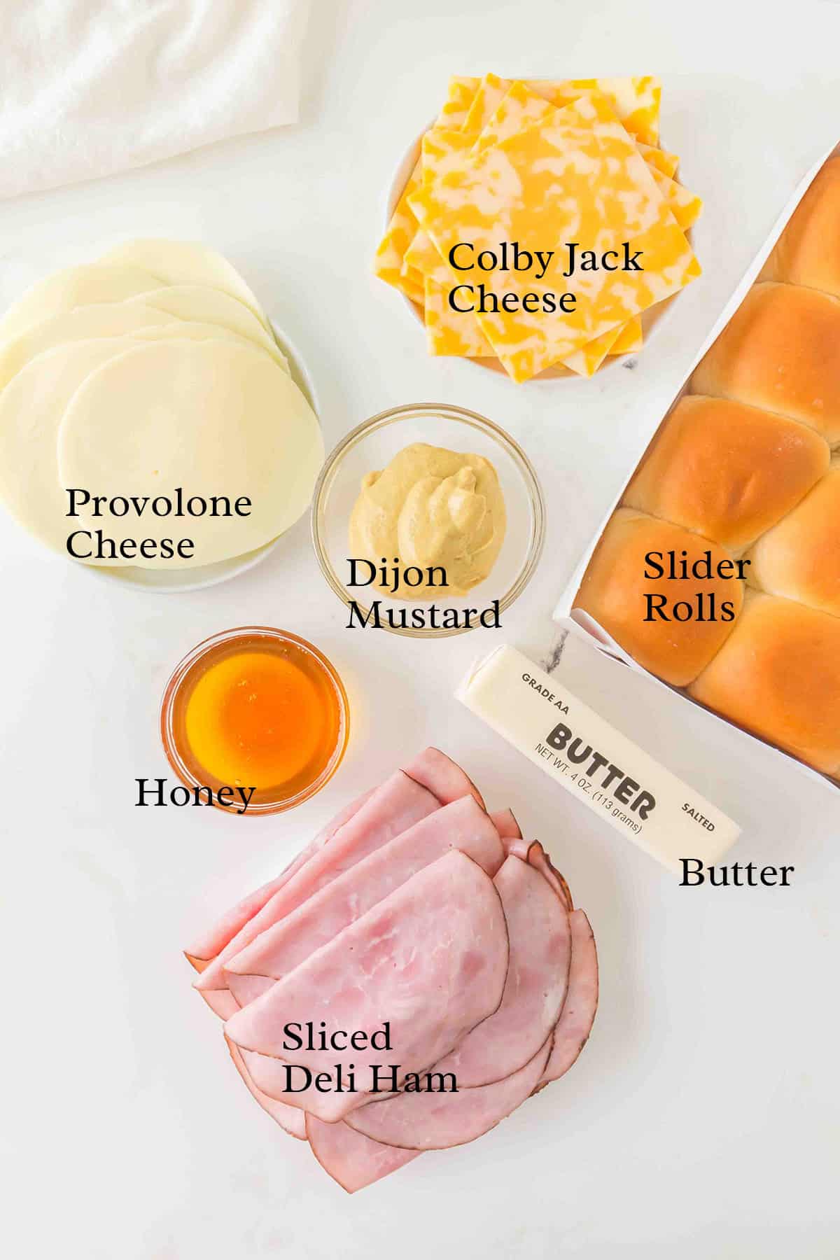 Ingredients for slider sandwiches: ham, provolone, Colby Jack, slider rolls, mustard, honey, and butter.