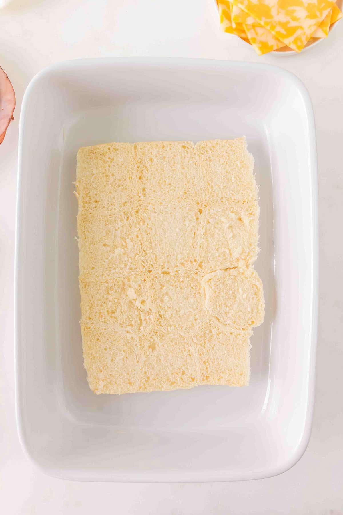 The bottom section of slider rolls, arranged in a white rectangular dish on a light surface.